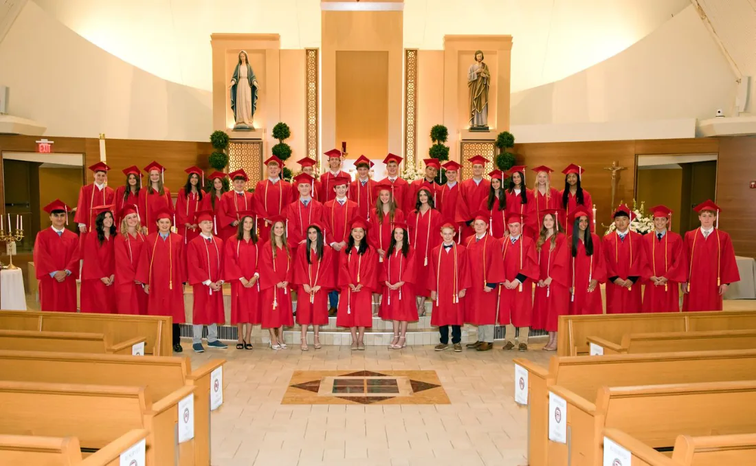St. Regis 8th grade graduates in red caps and gowns in church