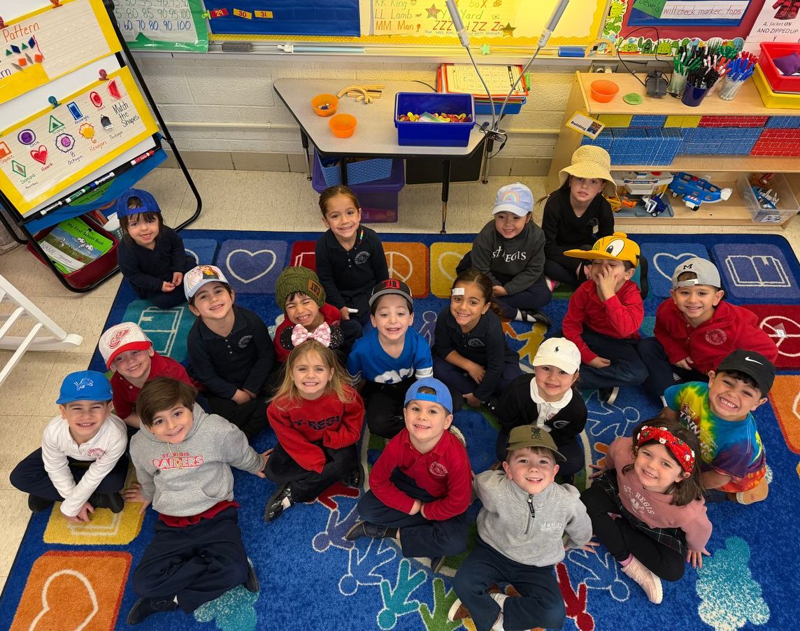 Young students in hats sitting together on the classroom rug