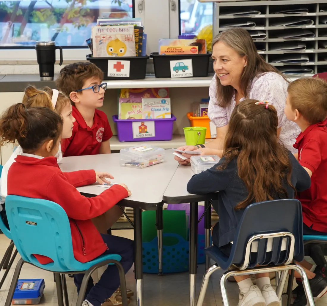 Teacher working with young students at a classroom table