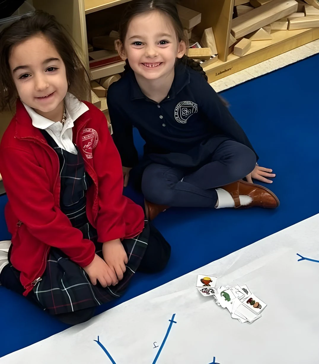 Two young students smiling on a classroom rug