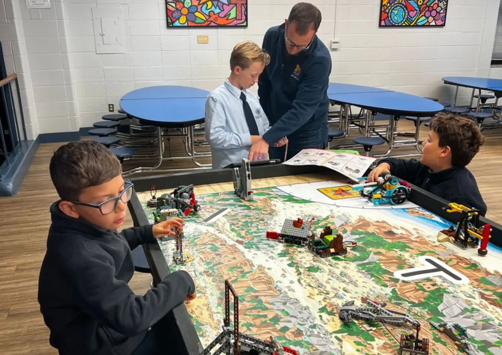 Students working on a robotics challenge with a teacher