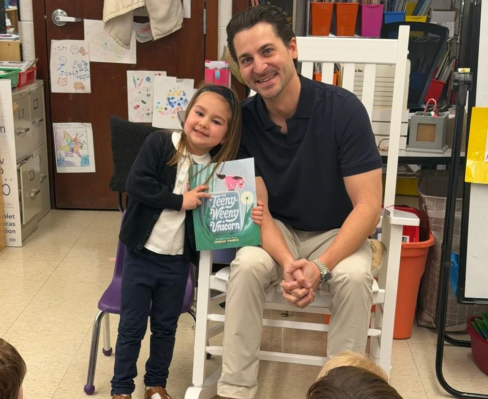 Student and her father sharing a book in a classroom