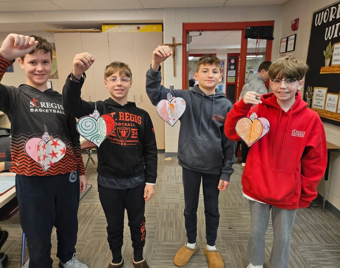 Academy students holding paper heart ornaments they made