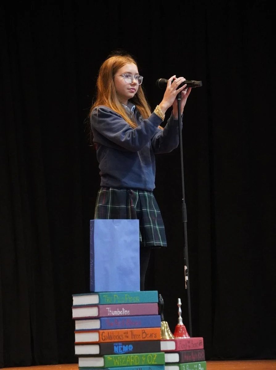 Student speaking at a microphone on stage