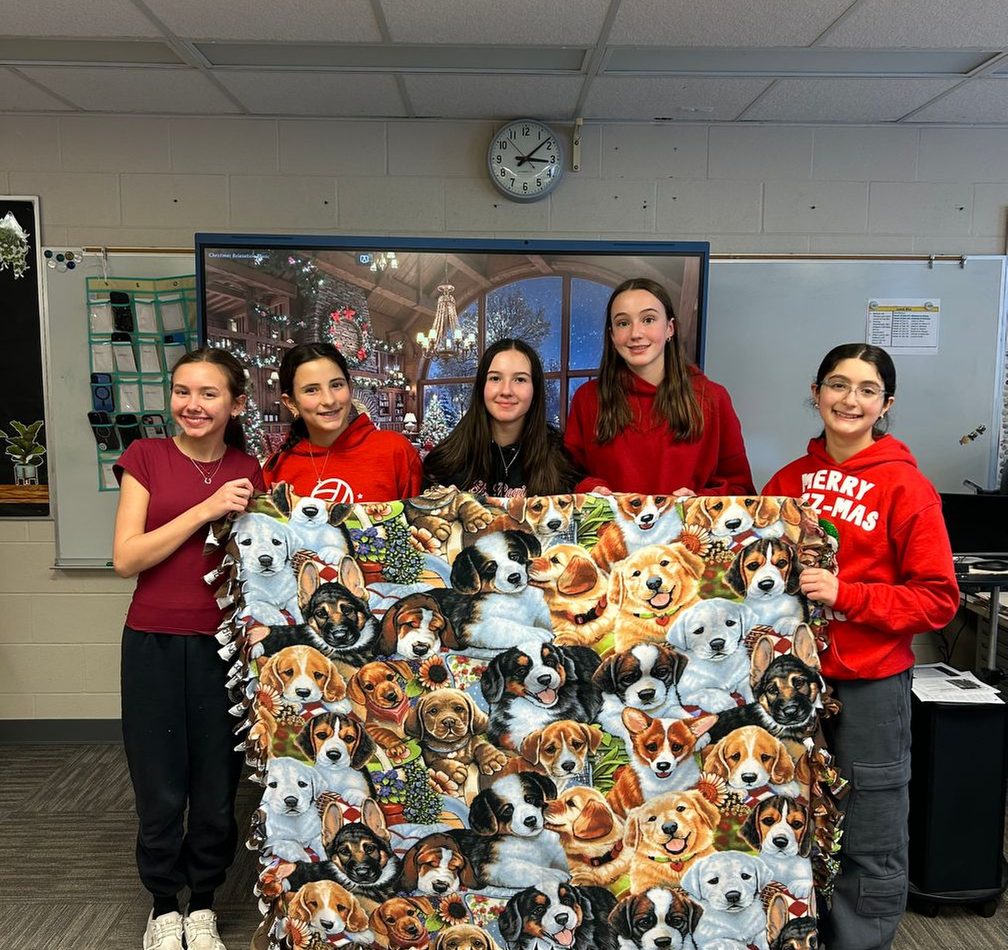 Students holding a handmade fleece blanket