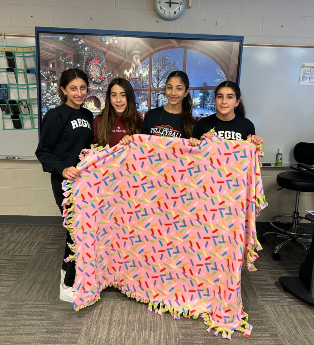 Students holding a handmade fleece blanket for a service project