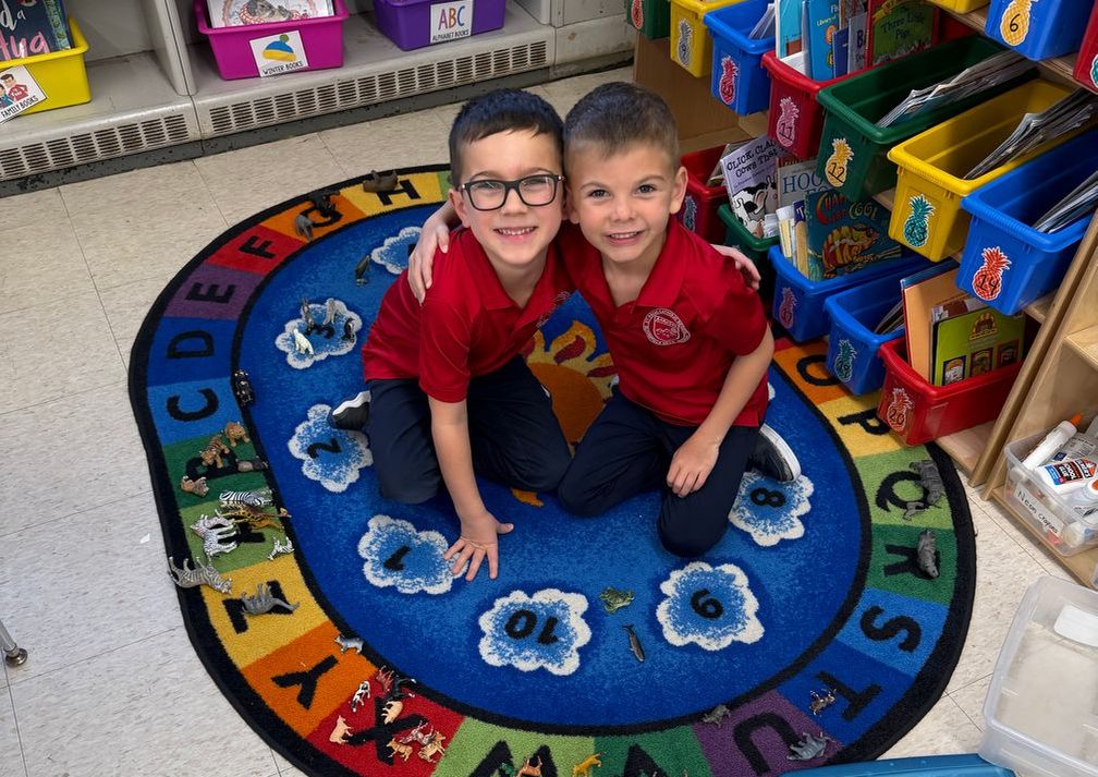 Two young students smiling together on the classroom rug