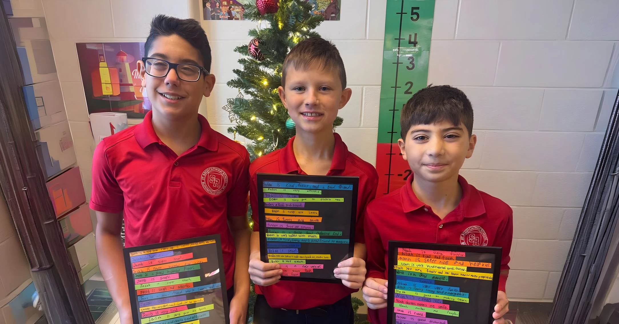 Three students holding their framed class projects